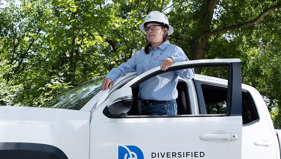 employee with hard hat in front of vehicle