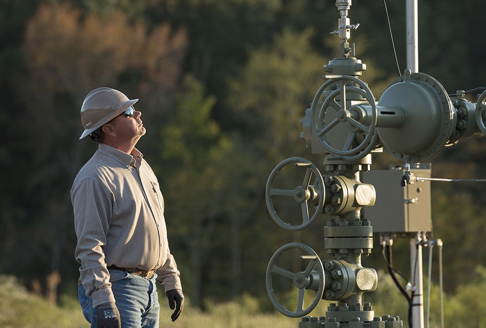 employee looking at natural gas equipment in the field